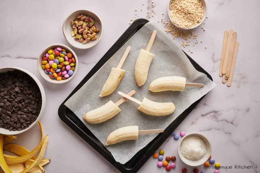 Cut the bananas in halves. Insert the wood sticks to make lollipops and place them in the freezer for 2 hours.
