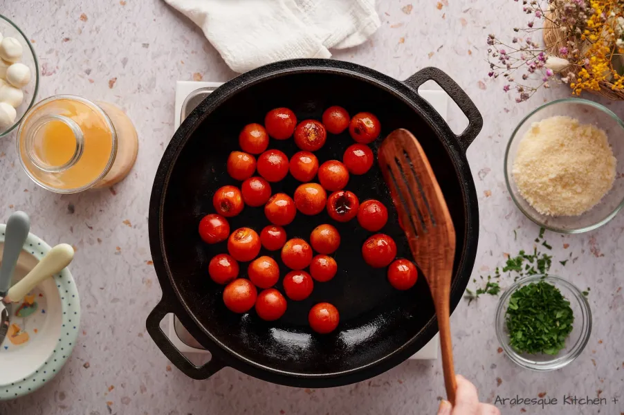 نضيف الطماطم الكرزية ونطهيها حتى تبدأ في التفتح (حوالي 10 دقائق).