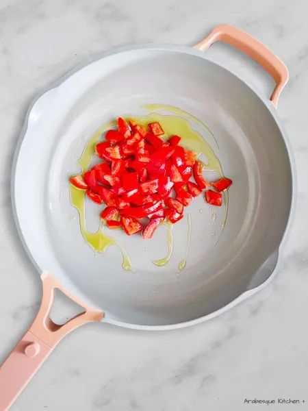 نسخن زيت الزيتون في مقلاة ونضيف الطماطم "منزوعة البذور ومقطعة إلى قطع بحجم 2 سم"