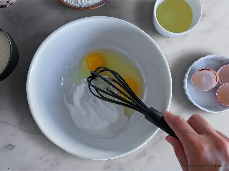 Mettez les gros œufs et le sucre en poudre dans un grand saladier et utilisez une fourchette ou un fouet pour les mélanger jusqu'à ce qu'ils soient bien combinés. Ajoutez l'huile de tournesol, le jus de citron, l'extrait de vanille et le sel et mélangez à nouveau jusqu'à obtenir un mélange homogène. 