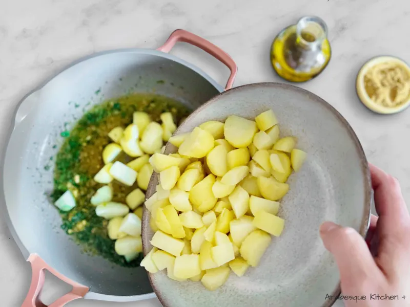 Faites chauffer l'huile d'olive dans une grande poêle et ajoutez l'ail épluché et écrasé, la coriandre, le sel et le cumin. Faites frire pendant quelques minutes jusqu'à ce qu'ils soient parfumés et ajoutez les pommes de terre. Goûtez et rectifiez l'assaisonnement en ajoutant du sel si nécessaire.