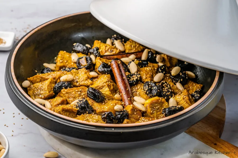 Top the meat with the plums and decorate the tagine with almonds and sesame seeds.
