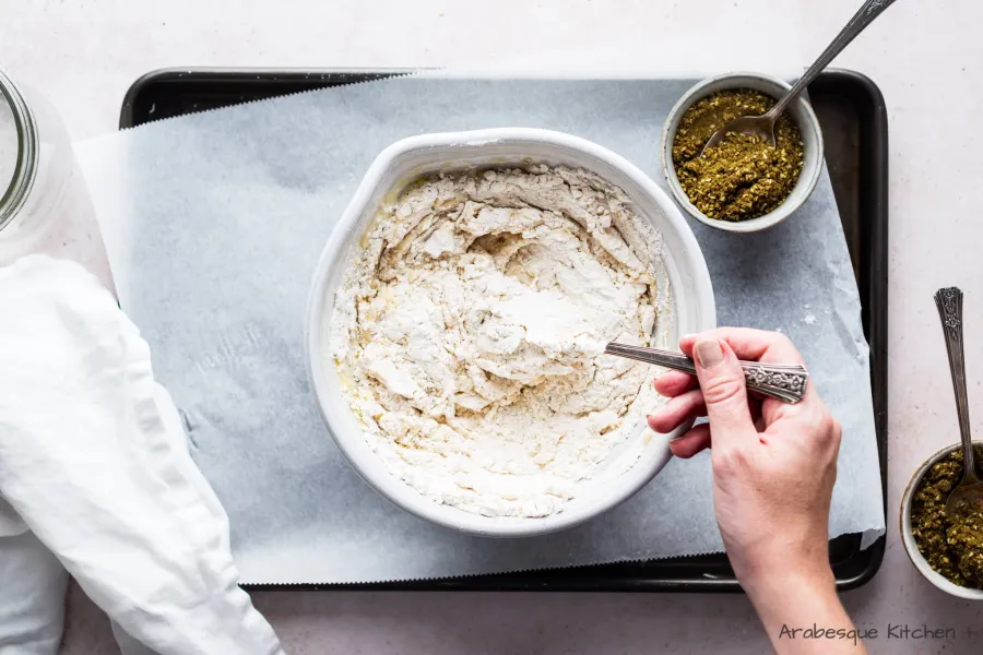 Combine with a spoon and start incorporating more water as it needs it, you will end up with a soft and sticky dough, but it should be dry enough so you can transfer to the table.
