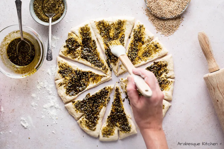 Cut the circle with a pizza cutter in 8 pieces, make a small cut in each of the short sides and top with the zaatar and oil mixture. 

