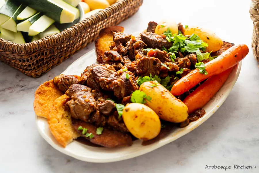 Dans un grand plat de service, superposer le regag grillé en ajoutant du bouillon pour qu'il soit mouillé. Verser sur la viande et les légumes et servir.
